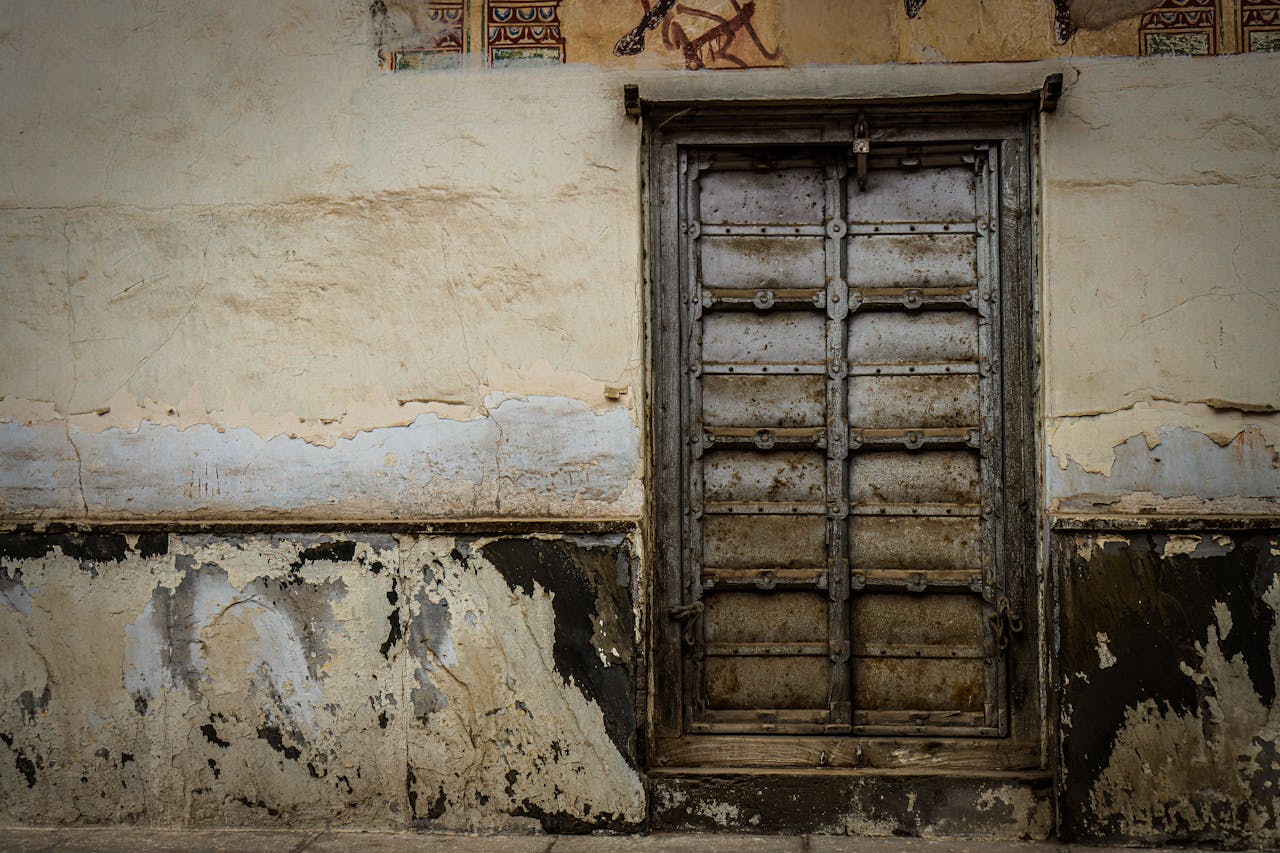 services-01 A rustic, weathered door on a decaying wall showcasing urban decay and texture.