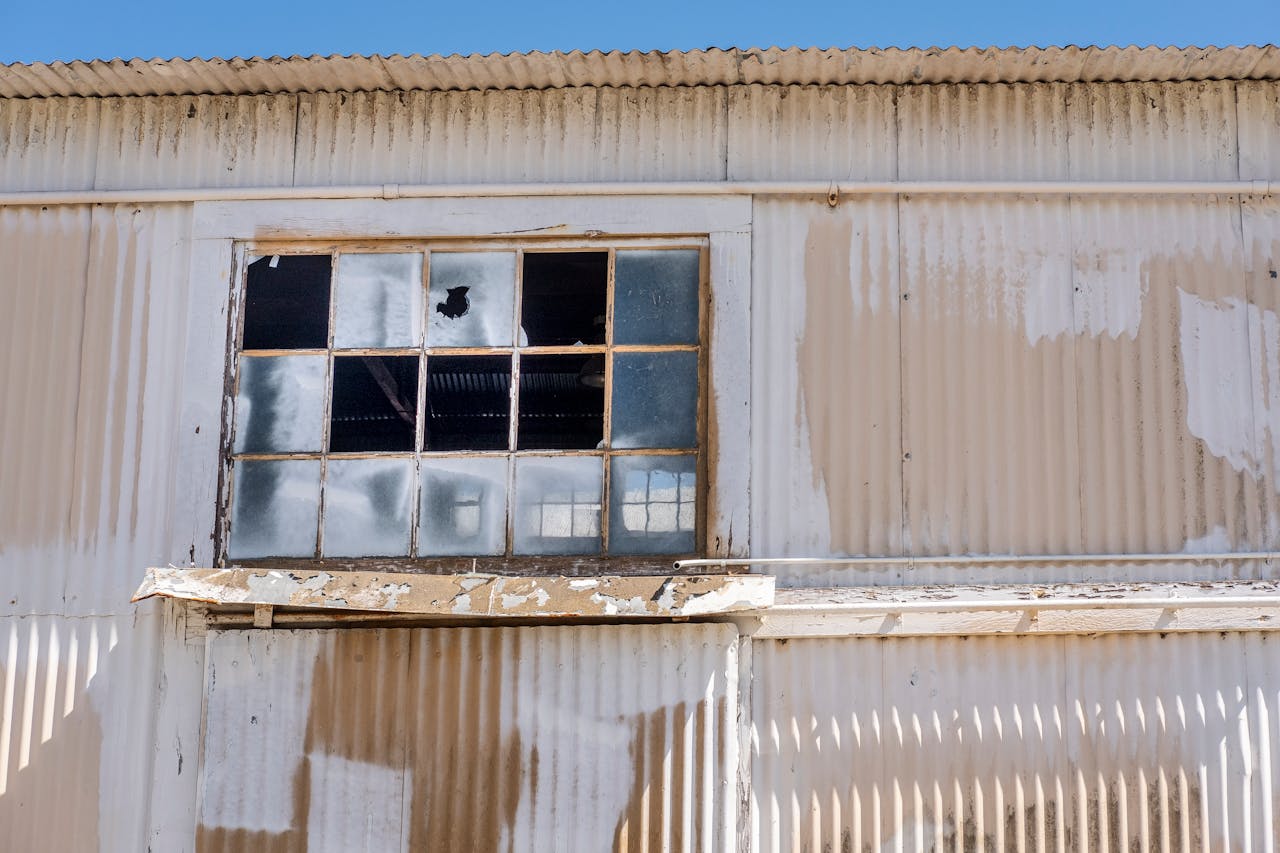 Close-up of an old industrial building's corrugated iron wall and broken window.